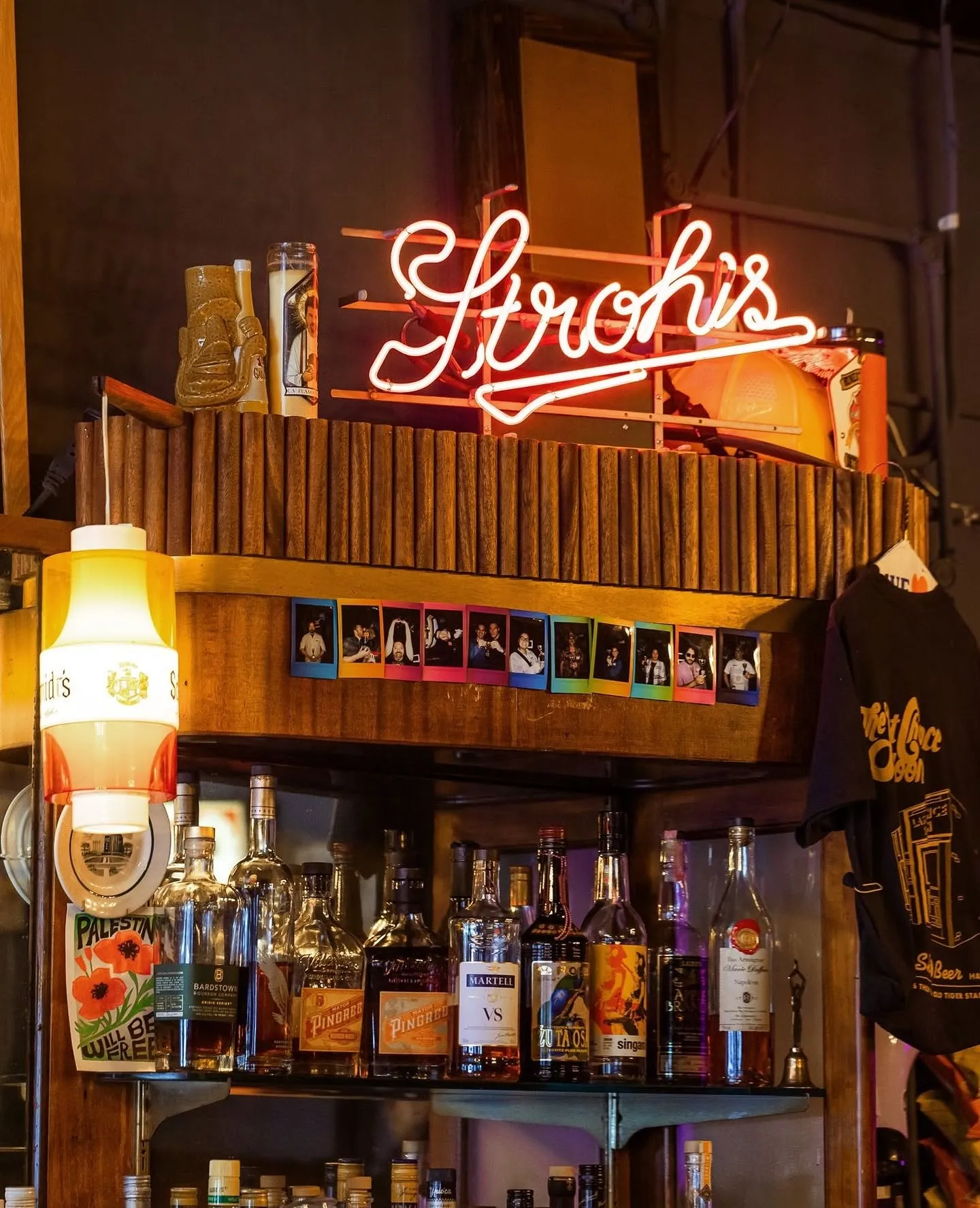 A glowing Stroh's sign and bottles above the bar