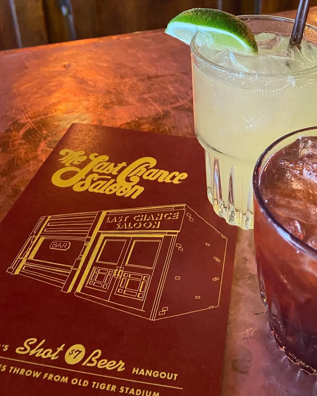 The Last Chance menu cover on the bar next to two drinks