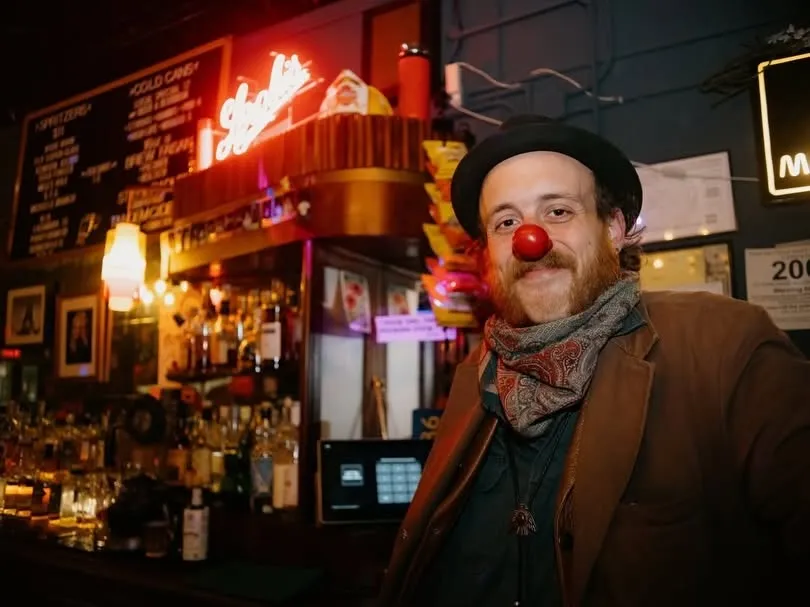 A magician in a red clown nose at the bar